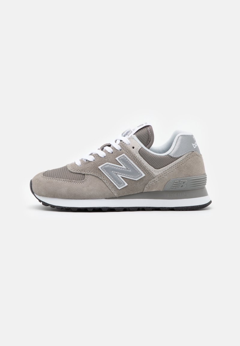 Baskets New Balance grises et blanches avec une tige en suède et mesh, lacets blancs et semelle en caoutchouc noire, vues de côté sur fond blanc.