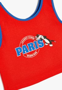 Röd ribbad crop top med blåa detaljer, med "PARIS" och "LOONEY TUNES SPORTS CLUB" i fet stil samt en illustration av en tecknad karaktär.