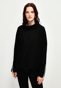 Maglione nero con collo a cowl e maniche lunghe, caratterizzato da strisce bianche a contrasto sui polsini. Realizzato in un morbido tessuto testurizzato.