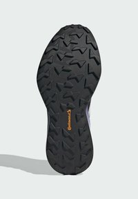Suela de goma negra con un patrón de textura y clavos angulares, destacada por un logo naranja de Continental cerca del centro.
