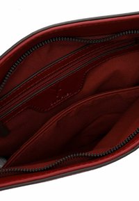 Interno rosso di una borsa con molteplici scomparti e cerniere. Presenta una trama liscia e una leggera lucentezza sul tessuto.