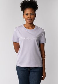 Lichtpaars katoenen T-shirt met een ronde hals en korte mouwen. Voorzien van een witte tekstprint op de borst. Gecombineerd met donkere spijkerbroek.