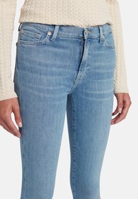 Jeans skinny in denim blu chiaro a vita alta, caratterizzati da un classico design a cinque tasche e dettagli di cucitura a contrasto.