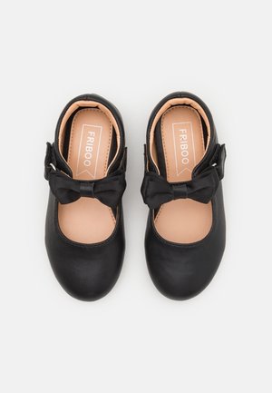 Zapatos Mary Jane negros para niños pequeños con correas de hebilla y lazos decorativos, suelas interiores beige con la etiqueta "FRIBOO", vistos desde arriba.