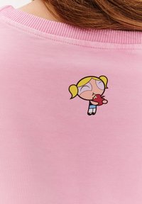 Růžová mikina s grafickým motivem kreslené postavičky na zádech, s žebrovaným límcem a měkkou bavlněnou texturou.