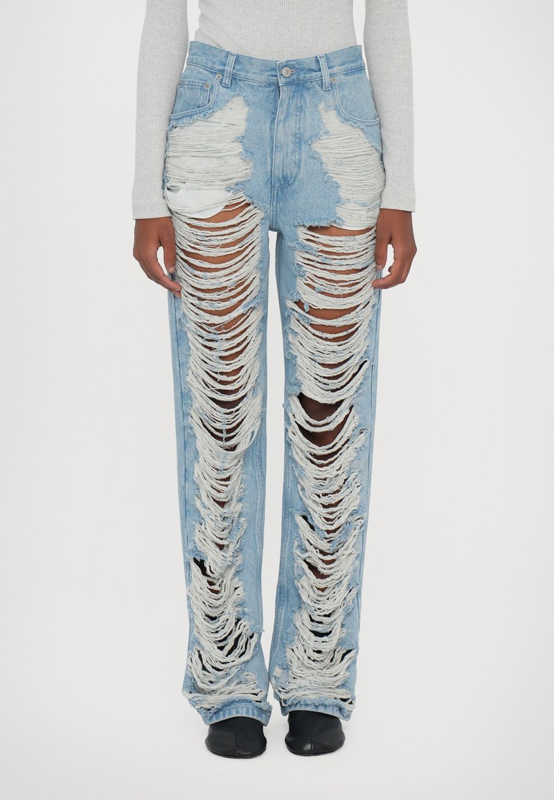 Jeans desbotados em azul claro com grandes rasgos, bordas desfiadas e um corte reto. Apresenta bolsos frontais e um design de cintura alta.