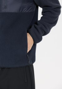 Marine fleece jacket met een ritssluiting aan de voorkant, gestructureerde stof en een glad bovenpaneel. Voorzien van zijzakken en elastische manchetten.