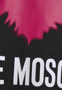 T-Shirt mit einem Farbverlauf-Design, das von Pink nach Schwarz verblasst, großen weißen Text am unteren Rand und einer glatten Baumwolltextur.