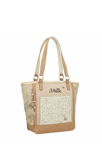 Sac fourre-tout beige avec un motif floral texturé, des accents en cuir, des poignées doubles et un attache-clés avec un charme en forme de cœur.