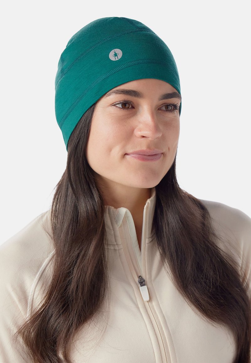 Berretto teal realizzato in un morbido e elastico tessuto, caratterizzato da una sottile etichetta con logo e dettagli cuciti per un tocco in più.