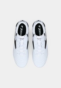 White athletic shoes with black accents, textured upper, lace closure, and "Joma" branding on the tongue and sides. Rounded toe design.