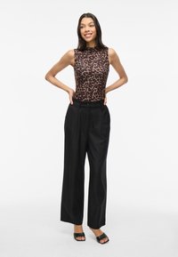 Leopard-print sleeveless top paired with high-waisted black wide-leg trousers. Smooth fabric with a glossy finish and a relaxed fit.