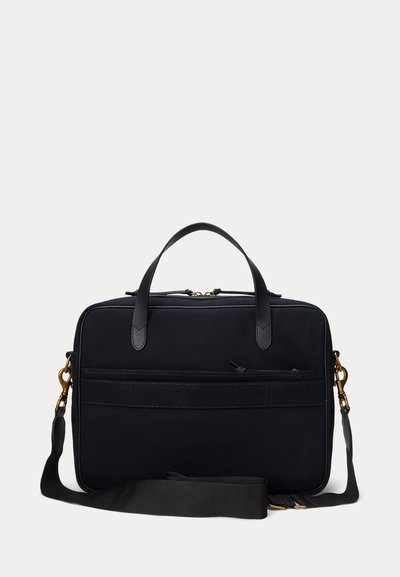 Pasta preta de lona com acabamentos em couro, alças duplas e uma alça destacável. Apresenta um bolso frontal com fecho e linhas limpas.