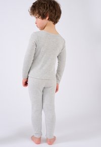 Pigiama grigio chiaro realizzato in materiale morbido, composto da una maglietta a maniche lunghe con scollo rotondo e pantaloni aderenti, indossato da un bambino.