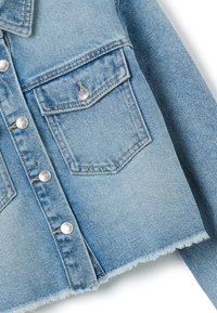 Veste en denim bleu clair avec des boutons en argent, poches avant, ourlet effiloché et tissage texturé distinct. Design classique avec un attrait décontracté.