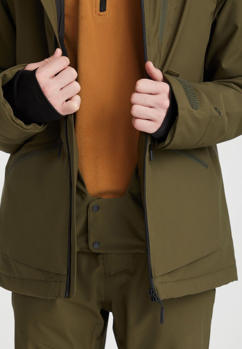 Olivgrüne Winterjacke mit einem frontalen Reißverschluss, kombiniert mit einer orangefarbenen Fleece-Innenlage. Die Jacke zeichnet sich durch eine glatte Textur und sichere Bündchen aus.