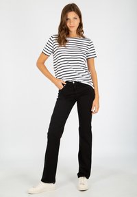 Randig svart och vit t-shirt med kort ärm, kombinerad med högmidjade svarta jeans och vita sneakers. Enkel, avslappnad stil.