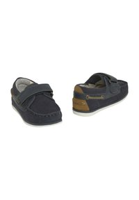 Zapatos de ante azul marino con una correa de velcro, detalles en marrón que contrastan, suela de goma blanca y costuras decorativas a lo largo del borde.