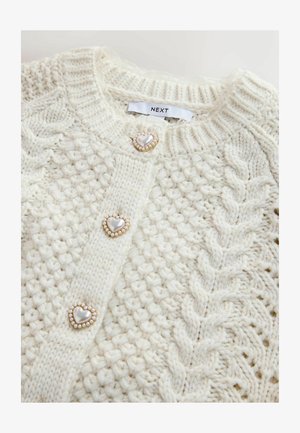 Cardigan tricotat crem cu model cu torsade, având nasturi în formă de inimă cu accente de perlă și guler cu dungi.