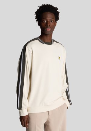 Light cream sweatshirt with dark gray and white side stripes, ribbed neckline, and small yellow logo on left chest. Smooth texture.
