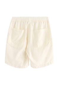 Krämfärgade shorts med elastisk midja, två bakfickor och mjuk tygkänsla. Enkelt design utan ytterligare mönster eller detaljer.