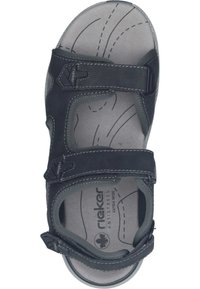 Czarne sandały z regulowanymi paskami, wyściełaną wkładką oraz teksturowaną podeszwą. Zauważalne detale obejmują białe szwy oraz przezroczysty logo marki.