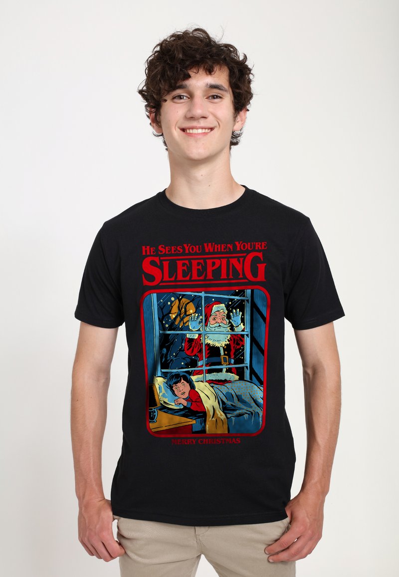 Camiseta de algodón negra con un gráfico colorido de Santa en una ventana, con el texto "Te ve cuando estás durmiendo" y "Feliz Navidad".
