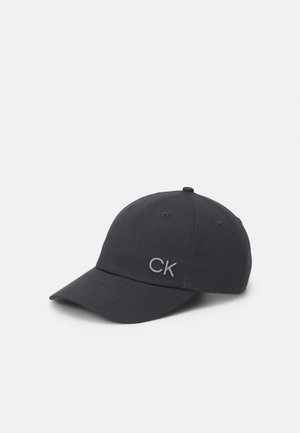 Boné de basebol preto em algodão com aba curva, apresentando o logo "CK" em cinza bordado na parte da frente e furos de ventilação na parte superior.