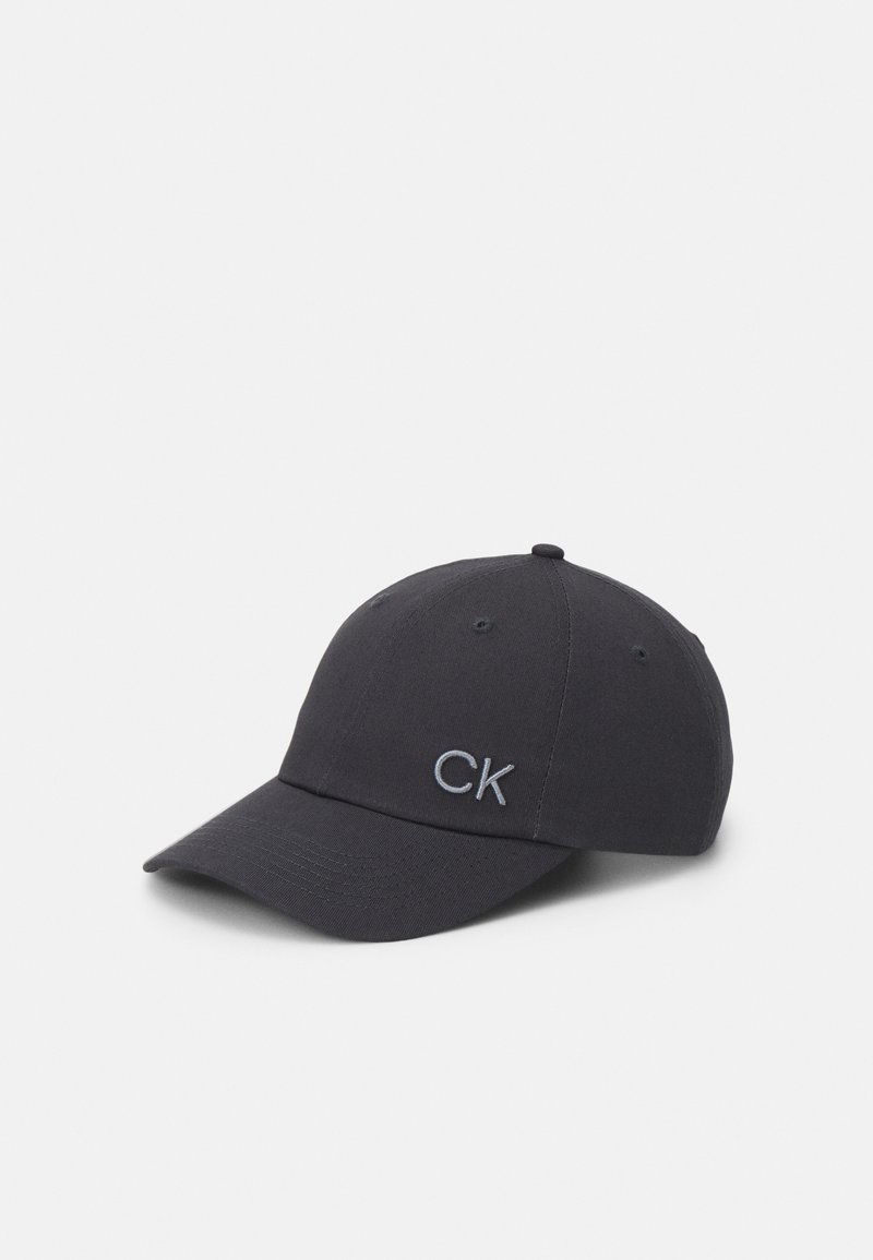 Čierna bavlnená baseballová čiapka s zakriveným okrajom, s šedým vyšitým logom "CK" na prednej strane a ventilačnými otvormi na vrchu.