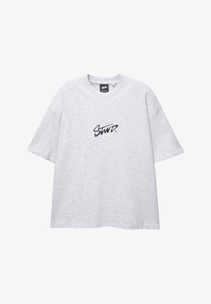 T-shirt grigia oversize in cotone con maniche corte e scollo rotondo. Presenta una stampa nera del logo sul davanti.