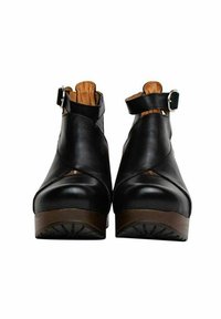 Zwarte leren enkellaarsjes met een ronde neus, zijkant met riem en gespsluiting, en een contrasterende bruine platformzool. Gladde textuur.