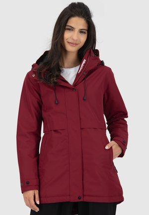 Veste imperméable rouge avec capuche, boutons sur le devant, cordons ajustables et poches latérales. Présente une texture lisse et un design moderne.