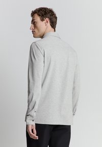 Grijze langemouwen shirt met een gestructureerde kraag, voorzien van een gladde textuur, knoopmanchetten en een iets ontspannen pasvorm.