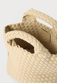 Beige πλεκτή τσάντα καλάθι με δύο καμπυλωτές λαβές. Διαθέτει περίτεχνη υφή και ορθογώνια ετικέτα επωνυμίας στο εσωτερικό. Ανθεκτικό υλικό, συμπαγής σχεδιασμός.