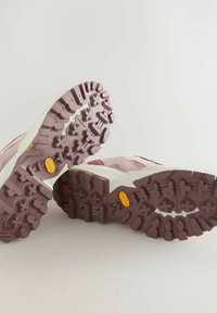 Trailrunning-Schuhe in zartem Pink mit weißen Akzenten. Sie verfügen über eine robuste Gummisohle mit tiefem Profil und einem Vibram-Logo.