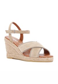 Beige wedge sandalen met een suède afwerking, open teenontwerp, crisscross banden en zilveren kraalaccenten. Stro gewikkeld platform.