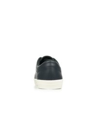 Sneaker in pelle blu navy con una texture liscia, suola in gomma bianca e design minimalista. Presenta linee curve e un profilo low-top.