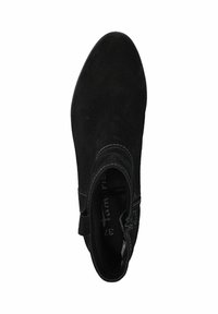 Czarny zamszowy botek do kostki o zakrzywionej sylwetce, z bocznym zamkiem i zielonym detalem szwu wokół kostki. Miękka tekstura, smukły design.