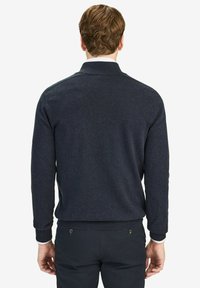 Tummansininen neulepaita, jossa on kauluspääntie, pitkät hihat, ribbaatut hihansuut ja sileä pinta. Ei näkyviä kuvioita tai yksityiskohtia.