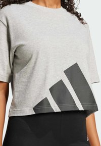 Grå kortärmad t-shirt i bomull med rund halsringning. Har en stor svart geometrisk grafik vid kanten och korta ärmar.