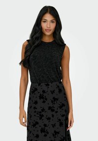 Czarna, bezrękawnikowa bluzka z fakturowanej tkaniny, zestawiona z długą czarną spódnicą z kwiatowym wzorem w ciemniejszych odcieniach.