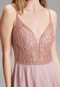 Różowa sukienka w odcieniu blush z koralikową siateczką w górnej części, posiadająca dekolt w kształcie litery V i cienkie ramiączka, opadająca w miękką spódnicę z szyfonu.