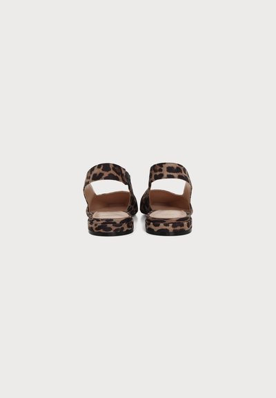 Par ravnih sandala sa remenima u leopard uzorku prikazanih s leđa na jednobojnoj svijetloj pozadini.