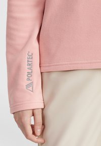 Light pink fleece pullover with a smooth texture, featuring a Polartec logo in silver embroidery on the left sleeve.