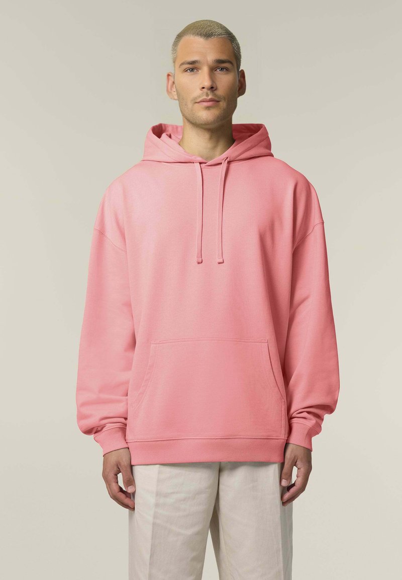 Felpa rosa realizzata in materiale morbido, con una tasca frontale, cappuccio con cordino e polsini a coste, abbinata a pantaloni leggeri e strutturati.