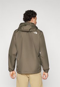 Jachetă impermeabilă de culoare verde măslin, cu glugă, manșete elastice, design simplu și detalii cu logo pe spate. Material neted și ușor.