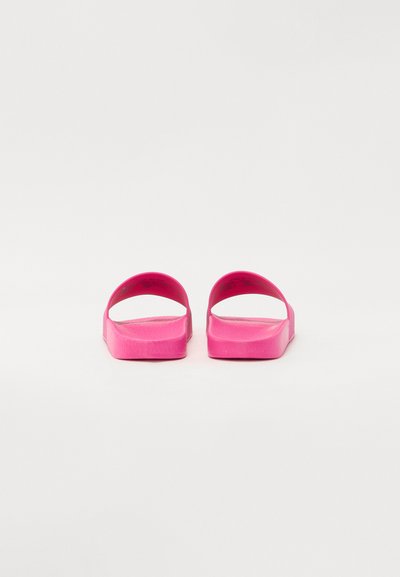 Ροζ ελαστικά σανδάλια slide με ανοιχτή πίσω πλευρά, φαρδιά λουράκια και υφασμάτινη επιφάνεια. Ισοπεδωμένη σόλα και μινιμαλιστικός σχεδιασμός.