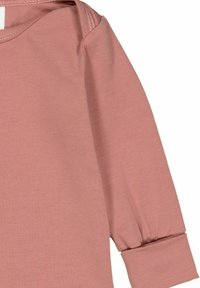 Světle růžový dlouhý rukáv oděv s nařasenými manžetami a hladkou texturou látky. Kulatý výstřih s jemným prošíváním.