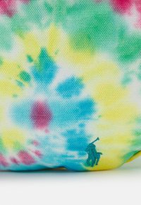 Materiał tie-dye w kolorach żółtym, niebieskim, zielonym i różowym, z małym haftowanym logo gracza polo w kolorze zielonym, umieszczonym blisko dolnej krawędzi.