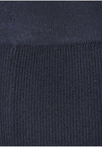 Krupan plan tamnoplave pletene tkanine koja prikazuje dva različita uzorka rebrastog bodova i horizontalni šav.